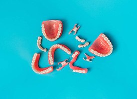 Bird’s eye view of several sets of full and partial dentures on a light blue background